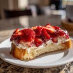 Eine Scheibe Erdbeer-Vanille-Schnitten mit frischen Erdbeeren und cremiger Vanillefüllung auf geröstetem Brot.