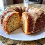 Anschnitt eines saftigen, gewürzten Apfelweinkuchens mit Ahornglasur auf einem weißen Teller.