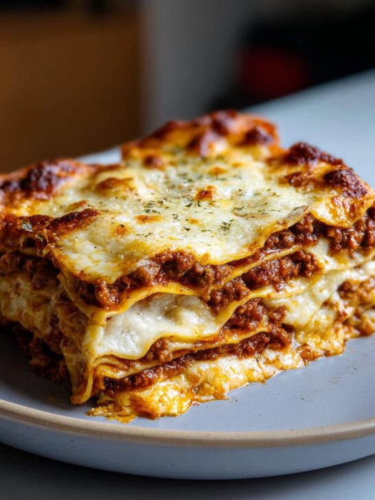 Ein perfekt geschichtetes Stück hausgemachte Lasagne al Forno mit viel Käse und Bolognese auf einem Teller.
