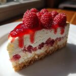 Ein saftiges Stück Himbeer-Mascarpone-Torte mit frischen Himbeeren und Himbeersoße auf einem weißen Teller.