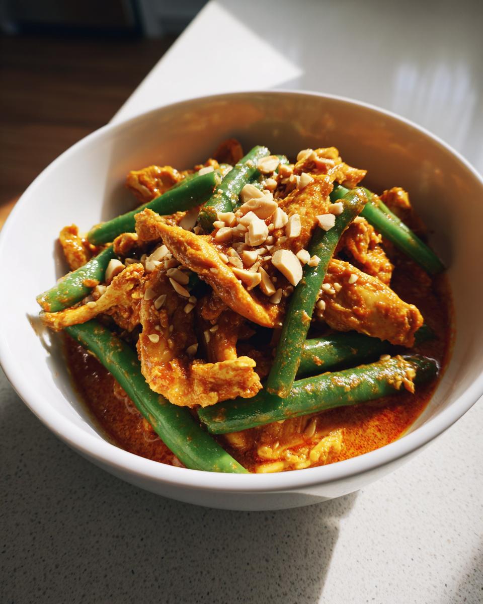 Eine Schüssel mit authentischem Kaeng Phanaeng, das mit Hühnchen, grünen Bohnen und gehackten Erdnüssen garniert ist.