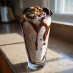 Ein leckerer Oreo-Milchshake mit Schokosauce und Keks-Stückchen, der in einem Glas serviert wird.