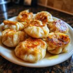 Nahaufnahme von goldbraun gebratenen Piroggen mit Pilzfüllung oder Quarkfüllung auf einem Teller.