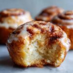 Nahaufnahme eines Cinnamon Roll Bites mit einem Bissen herausgebissen, der den weichen Teig und den Zimt zeigt.