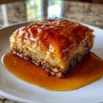 Ein Stück Baklava mit Walnüssen und Honigsirup auf einem Teller, goldbraun gebacken und glänzend.