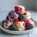 Ein Haufen selbstgemachter Frozen Yogurt Bites mit Beeren, bedeckt mit Brombeeren und Himbeeren.