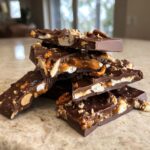 Nahaufnahme von gestapelten Stücken Karamell-Pretzel-Chocolate-Bark mit dunkler Schokolade, Karamell und Salzstücken.