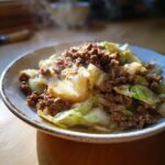 Nahaufnahme einer dampfenden Hackfleisch-Kohlpfanne Hausmannskost in einer rustikalen Schale.