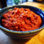 Nahaufnahme einer blauen Schüssel gefüllt mit hausgemachtem Ajvar – Paprikapaste.