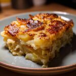 Ein Stück goldbraun gebackenes Kartoffelgratin mit Lauch und Käse auf einem Teller.