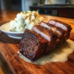 Aufgeschnittener, kross gebratener Kasseler auf einer Soße, serviert mit Rahmkohlrabi.