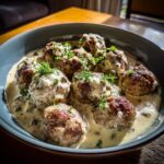 Königsberger Klopse mit Kapernsauce in einer Schüssel, garniert mit frischen Kräutern.