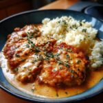 Ein Teller mit saftigem Paprika-Sahne-Schnitzel und cremigem Butterreis, garniert mit frischen Kräutern.