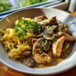 Nahaufnahme von Pilzrahm-Geschnetzeltes mit Spätzle, garniert mit Petersilie.