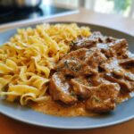 Nahaufnahme von Rahmgeschnetzeltes Schnitzel-Streifen mit Bandnudeln auf einem Teller, appetitlich serviert.