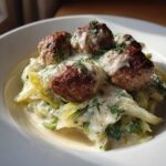 Nahaufnahme von saftigen Frikadellen auf cremigem Rahmwirsing, garniert mit frischem Dill.