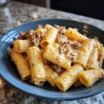 Eine köstliche Portion Rigatoni mit Hackfleisch-Sahne-Sauce in einer blauen Schüssel, bereit zum Genießen.