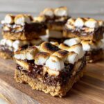 Nahaufnahme eines Anschnitts von S’mores Cookie Bars mit knusprigem Boden, Schokolade und getoasteten Marshmallows.
