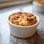 Nahaufnahme von frisch gebackenem Baked Oats mit Eiweißpulver in einer weißen, geriffelten Auflaufform.