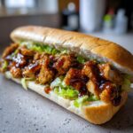 Nahaufnahme eines saftigen Chicken Teriyaki Sandwich mit knusprigen Hähnchenstücken und Teriyaki-Sauce auf Salat.