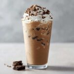 Ein hoher, kühler Cookies & Cream Frappuccino mit viel Sahne und Keksstückchen obenauf.