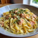 Nahaufnahme von Cremige Lachs-Sahne-Pasta mit breiten Bandnudeln in cremiger Soße, belegt mit Lachs und frischem Dill.