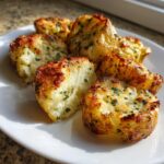 Mehrere goldbraun gebackene Knoblauch-Parmesan Ofenkartoffeln mit Petersilie auf einem weißen Teller.