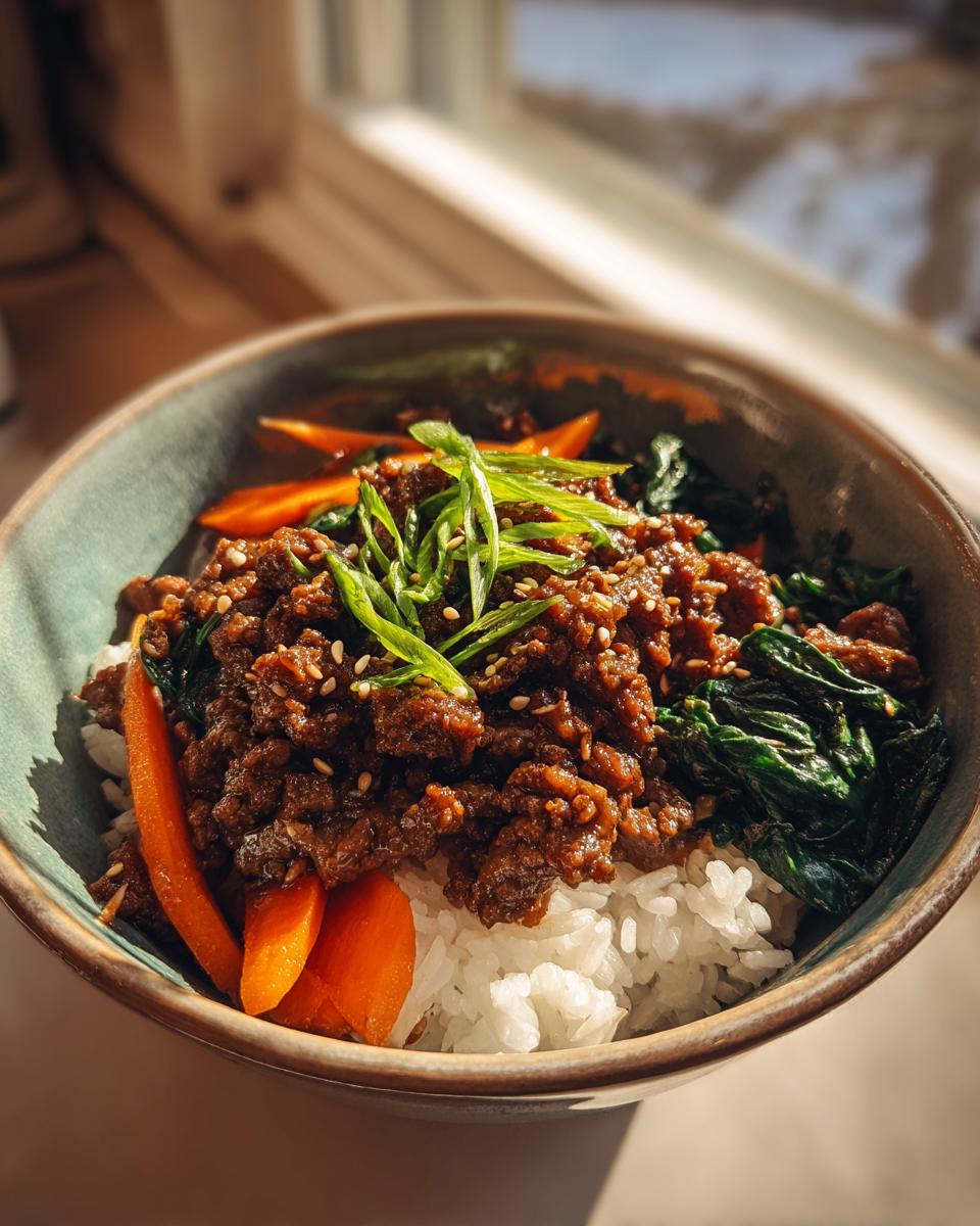 Nahaufnahme eines Korean Beef Bowl mit Rinderhack, Reis, Karotten und Frühlingszwiebeln.