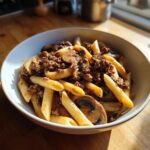 Nahaufnahme einer Schüssel mit One-Pot Jäger-Hack-Pasta, gefüllt mit Penne, Hackfleisch und Pilzen.