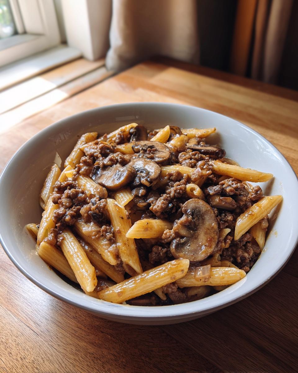 Nahaufnahme einer Schüssel mit One-Pot Jäger-Hack-Pasta, gefüllt mit Penne, Hackfleisch und Pilzen.