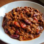 Nahaufnahme von cremigem, würzigem Pikantes Chili con Carne mit viel Hackfleisch und roten Kidneybohnen in einer weißen Schale.