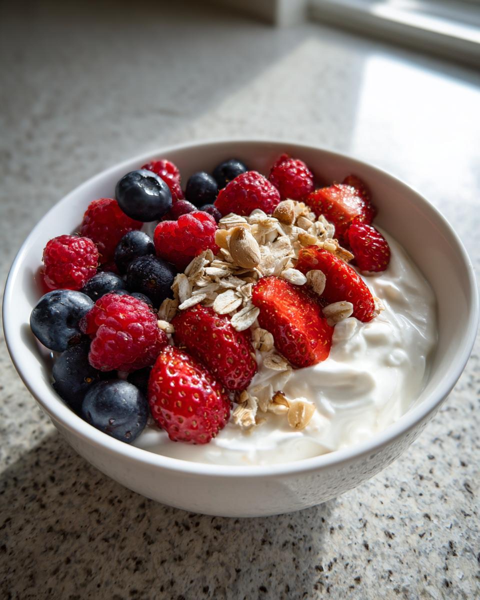 Nahaufnahme einer cremigen Skyr-Bowl mit Haferflocken, Himbeeren, Blaubeeren und Erdbeeren.