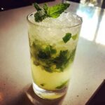 Nahaufnahme eines hohen Glases mit Super erfrischende Minzlimonade, gefüllt mit zerstoßenem Eis und frischen Minzblättern.