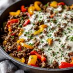 Nahaufnahme der Ungarische Hackfleischpfanne mit Kräuter-Sahnesoße, Hackfleisch und bunten Paprikastreifen.