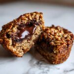 Nahaufnahme eines aufgeschnittenen Baked-Oats mit flüssigem Schokokern, der warm herausläuft.
