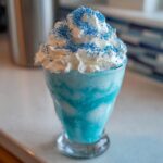 Nahaufnahme eines leuchtend blauen Blue-Lagoon-Milchshake mit viel Sahne und blauen Zuckerperlen.