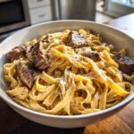 Nahaufnahme einer Schüssel mit cremiger Steak-Pasta, garniert mit Parmesan und Pfeffer.