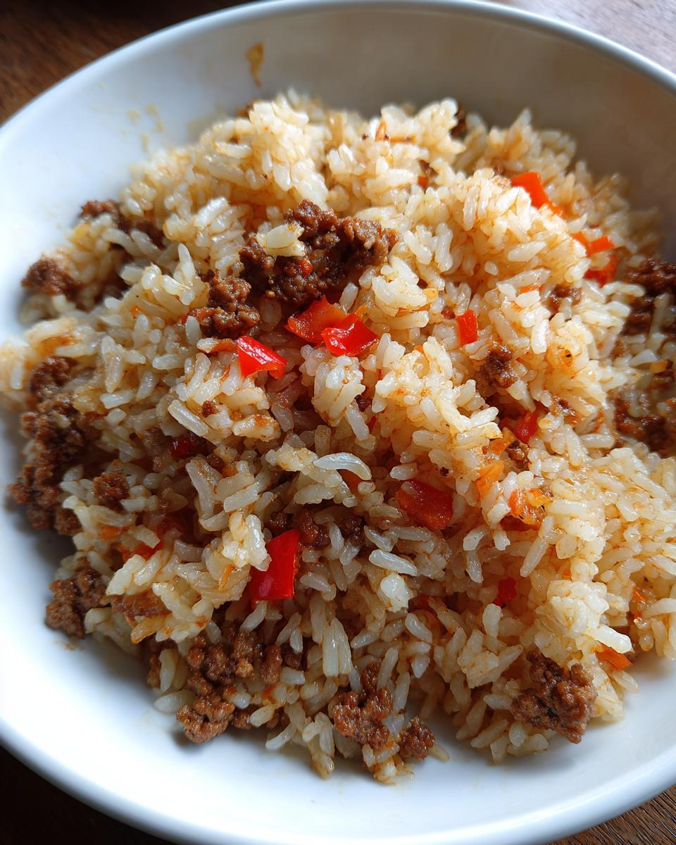 Eine Schüssel mit aromatischem Djuvec-Reis mit Hackfleisch und roten Paprikastückchen.