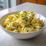 Nahaufnahme von cremigem Eiersalat wie früher, garniert mit frischem Schnittlauch, in einer weißen Schüssel.