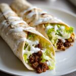 Zwei saftige Wraps mit Hackfleisch, knackigem Salat und cremiger Knoblauchcreme auf einem weißen Teller.