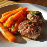 Zwei goldbraun gebratene Frikadellen mit glänzendem Möhrengemüse, garniert mit Petersilie.