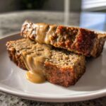 Zwei saftige Scheiben Hackbraten, übergossen mit cremiger Rahmsauce, auf einem weißen Teller.