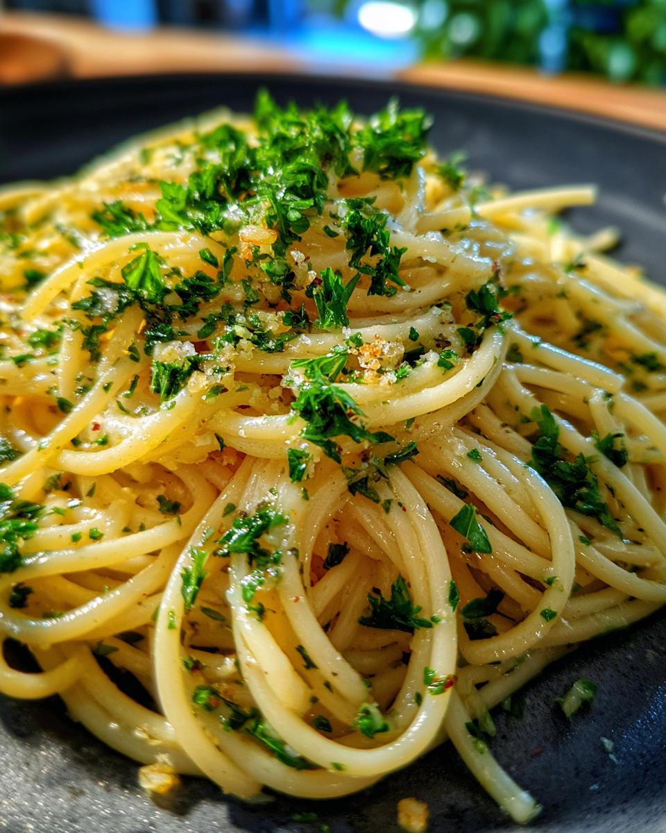 Nahaufnahme von saftigen Nudeln mit Butter, Knoblauch und Petersilie, reichlich bestreut mit frischem Grün.
