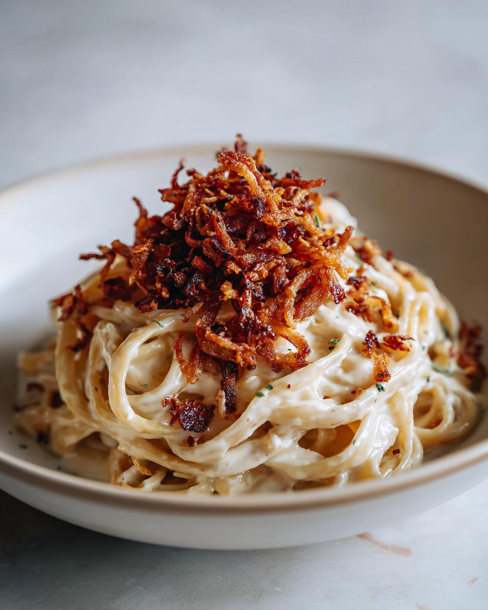 Nahaufnahme von Nudeln mit Sahne und Röstzwiebeln, üppig garniert mit knusprigen Röstzwiebeln.