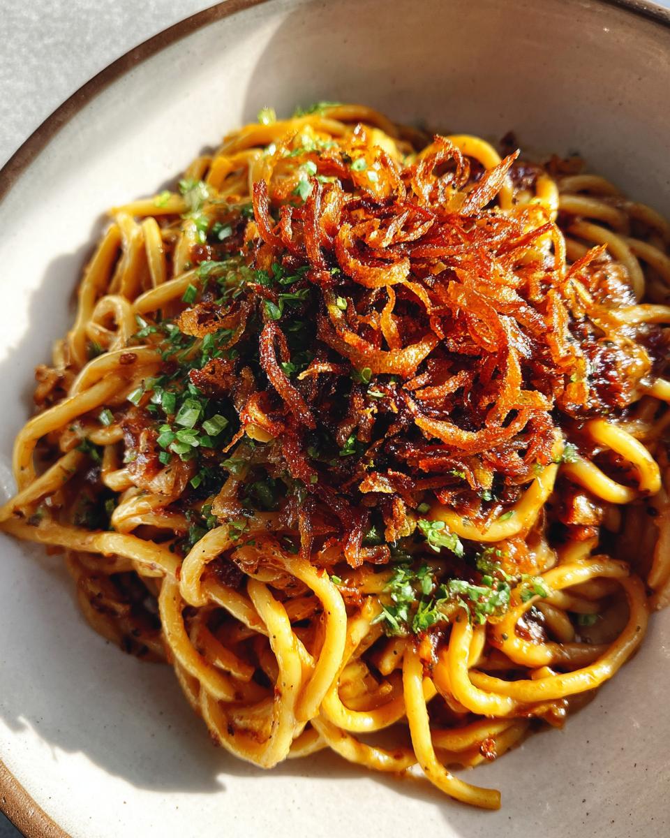 Eine Schüssel mit cremigen Nudeln mit Sahne und Röstzwiebeln, garniert mit knusprigen Röstzwiebeln und frischer Petersilie.