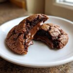 Aufgeschnittener, schokoladiger Nutella-Lava-Cookie mit flüssigem Kern auf einem weißen Teller.