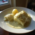 Nahaufnahme von Rahmkohlrabi mit Kartoffeln in einer hellen Rahmsauce auf einem weißen Teller.