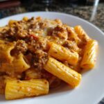 Teller mit cremigen Rigatoni mit Hackfleisch-Käsesauce und geschmolzenem Käse.