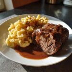 Ein Teller mit saftigen Rinderrouladen mit dunkler Soße und frischen Spätzle.