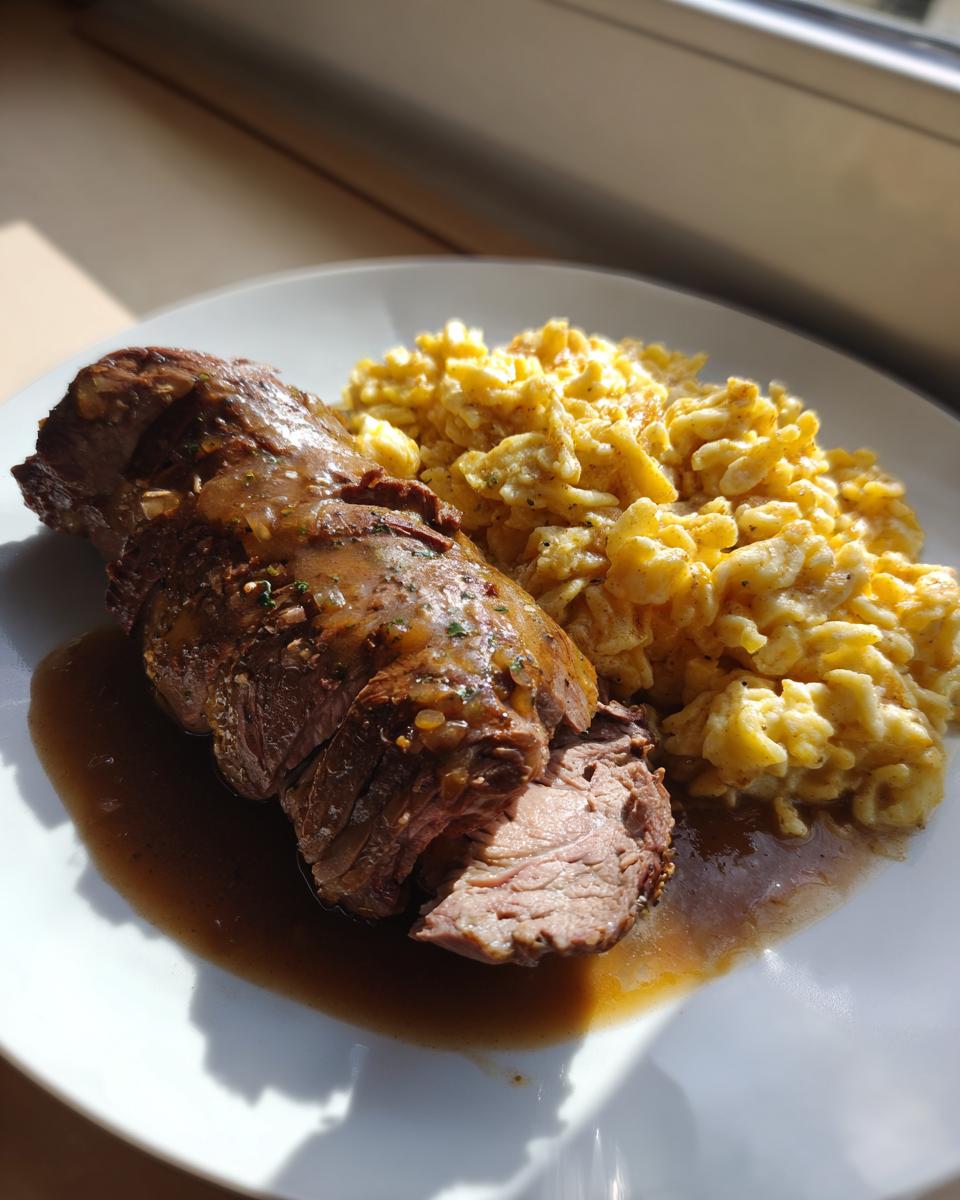 Ein Teller mit saftigen Rinderrouladen mit dunkler Soße und einer Portion goldgelber Spätzle.